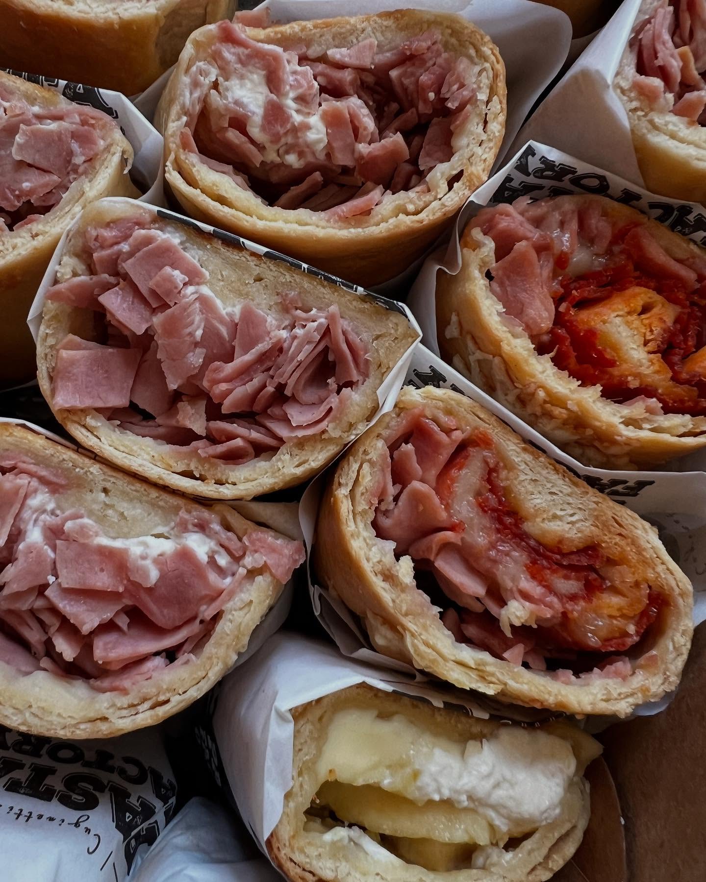 Panecillos rellenos de jamón y queso, envueltos en papel con la marca Pasta Factory