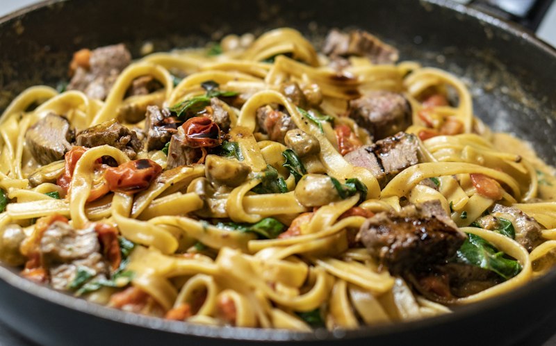 Pasta salteada con hongos servida directamente en la sartén